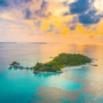 A breathtaking aerial view of a vibrant sunset over a tropical island in the Maldives, surrounded by turquoise waters.