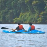 Two men enjoying a kayaking adventure on a tranquil river surrounded by lush greenery.